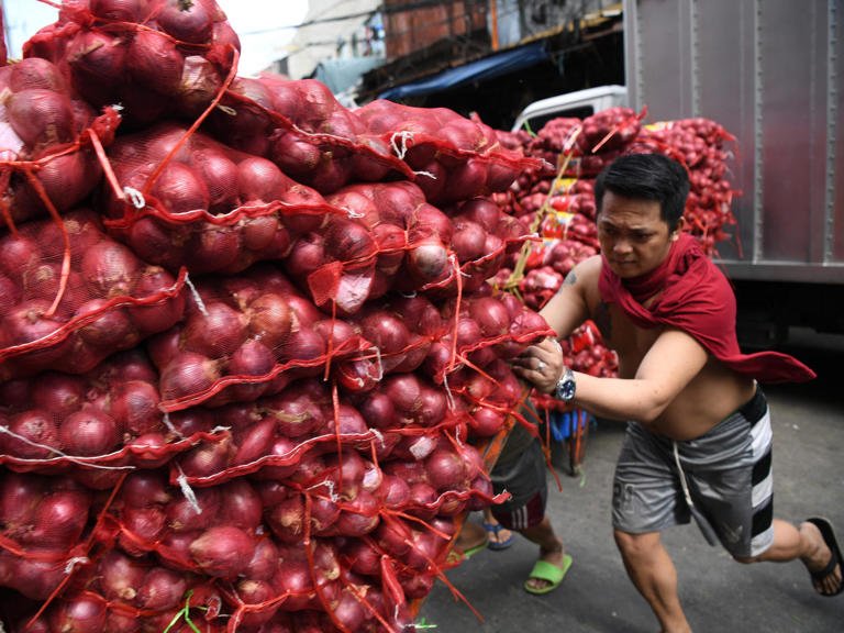 Workers push a trolley of imported onions in Manila TED ALJIBE/AFP via Getty Images