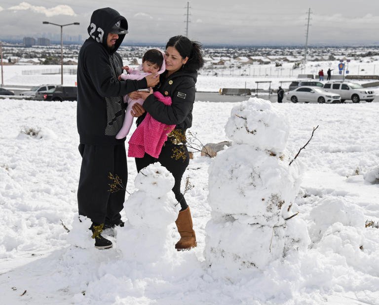 (L-R) Armando Garcia, 7-month-old Bella Garcia and Bella Garcia, all of Nevada, prepare to take a photo with snowmen they built on the west side of town during a winter storm on February 21, 2019 in Las Vegas, Nevada. Las Vegas was once again hit with snow on Tuesday.