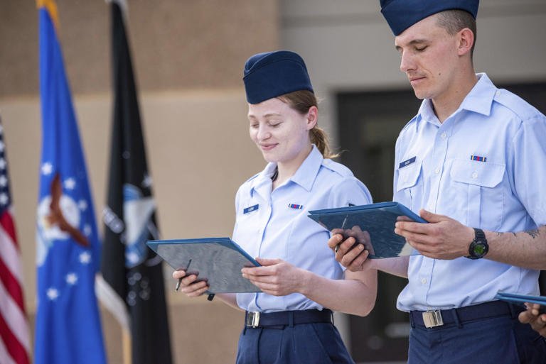 Airman 1st Class Natalia Laziuk, from Russia, left, and Airman 1st Class Ross Mudie, from South Africa, look at their U.S. Certificates of Citizenship after signing it following the Basic Military Training Coin Ceremony on April 26, 2023, at Joint Base San Antonio-Lackland, Texas. The U.S. military has struggled to overcome recruiting shortfalls and as a way to address that problem, it's stepping up efforts to sign up immigrants, offering a fast track to American citizenship to those who join the armed services. (Christa D'Andrea/U.S. Air Force via AP)