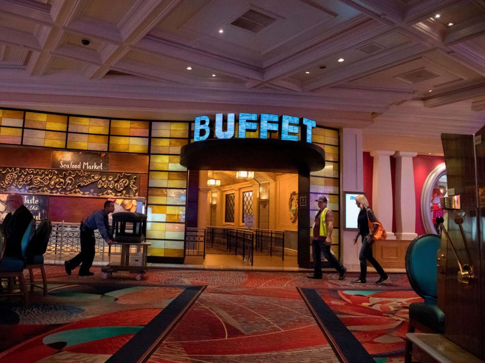 The entrance to The Buffet at Bellagio is inside the Las Vegas hotel. A bright blue sign is illuminated above the doorway, enticing customers in.