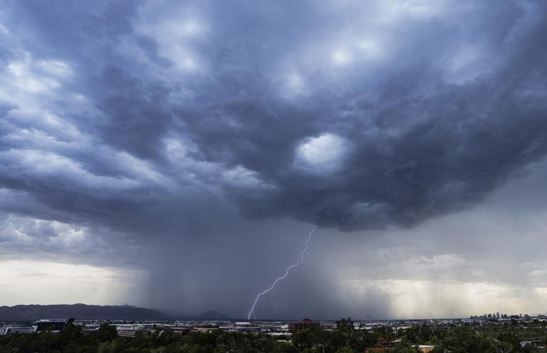 Lightning strikes as a monsoon thunderstorm dumps rain over south Phoenix on Sunday, June 26, 2022.