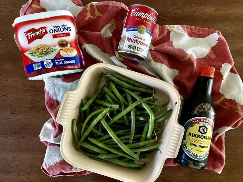 a tray of food and a bottle on a table: Green bean casserole is a classic Thanksgiving side and easy to make even if you choose to use fresh green beans instead of canned or frozen.