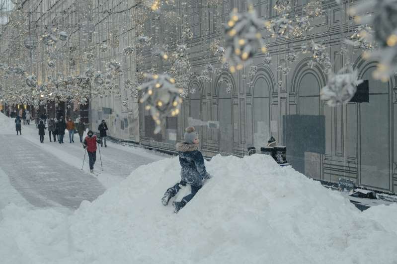 a group of people riding skis across snow covered ground: A boy plays in the snow next to Red Square on Feb. 13.