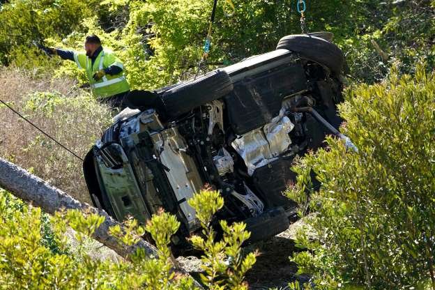 Slide 5 of 9: Workers move a vehicle on its side after a rollover accident involving golfer Tiger Woods on Feb. 23, 2021, in the Rancho Palos Verdes section of Los Angeles.