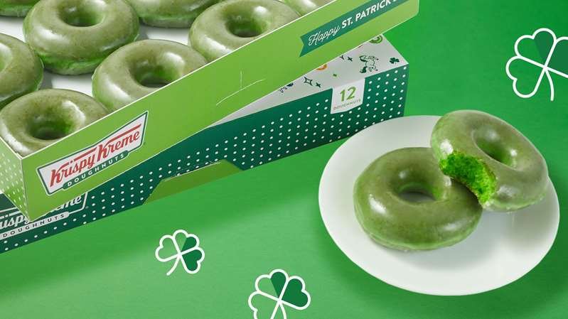 a donut sitting on top of a green box on a table: Krispy Kreme has special doughnuts for St. Patrick's Day.