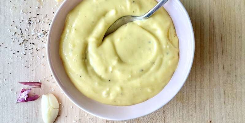a bowl of fruit on a plate: Wondering how to make garlic aioli from scratch? It's not hard at all! If you have egg yolks, garlic, lemon juice and olive oil, then you're on your way!