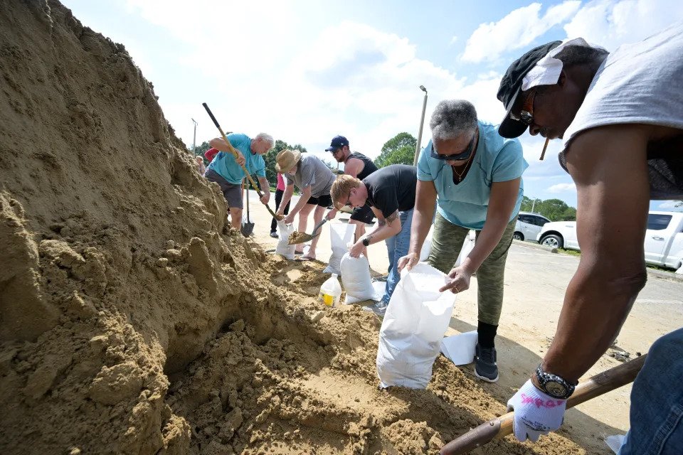 Johnny Ford, right, and his wife Jerria Ford fill free sandbags in preparation for the arrival of Hurricane Ian,
